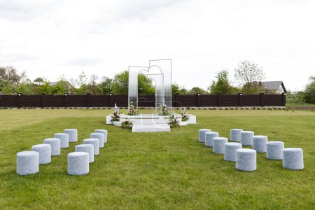 A cluster of stools placed in the middle of a grassy field, creating an unexpected scene in a natural setting.