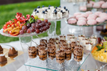 A table overflowing with a variety of desserts, including colorful cupcakes, pastries, tarts, and cakes, creating a tempting display.