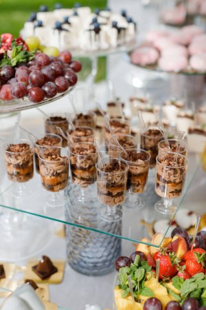 Une table en bois présente une variété de desserts et de cupcakes dans des emballages colorés et des glaçages, créant une propagation tentante et délicieuse.