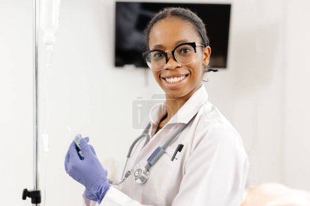 Eine Ärztin mit weißem Mantel und blauen Handschuhen, die bereit ist, Patienten in einem medizinischen Umfeld beizustehen.