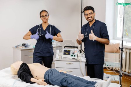 Deux médecins en tenue d'hôpital debout au-dessus d'un mannequin médical, examinant et discutant des procédures et techniques médicales.