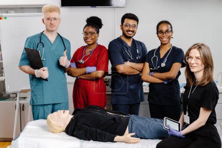 A group of doctors in medical scrubs standing around a mannequin lying on a hospital bed, discussing and examining the patients condition