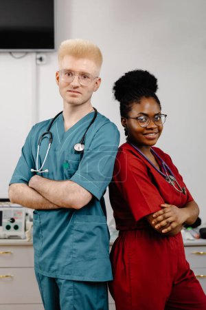 Deux professionnels de la santé, vêtus de manteaux blancs, se tiennent côte à côte dans un hôpital. Ils semblent concentrés et engagés dans la conversation ou la consultation.