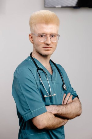 A male healthcare professional wearing a green scrub suit is pictured with a stethoscope around his neck, ready to provide medical care.