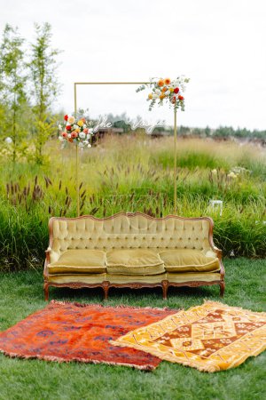 A couch and a rug placed on the grass outside, creating a seating area in an outdoor setting.