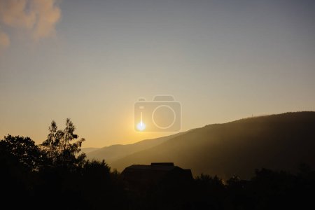 Photo for The sun is in the process of setting behind the mountains in the distance, casting long shadows and painting the sky with warm colors. - Royalty Free Image
