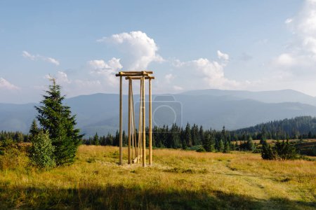 A tall wooden structure stands prominently in the center of a vast field, surrounded by open space and under a clear sky.