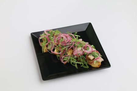 Sliced Herring with mini potatoes and red onion on dark plate top view on white background.