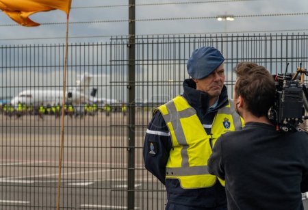 Foto de Schiphol Airport Amsterdam, Países Bajos, 05.11.2022, Portavoz de la Royal Netherlands Marechaussee Robert Van Kapel siendo entrevistado durante la acción de protesta de activistas climáticos en el aeropuerto - Imagen libre de derechos