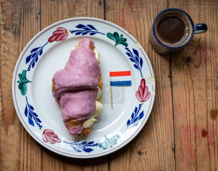 Ein Crompouce mit holländischer Flagge und einem Kaffee. Eine Kreuzung aus Tompouce und Croissant, die aus den Niederlanden stammt