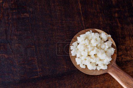 Milk kefir grains on wooden spoon isolated, copy space