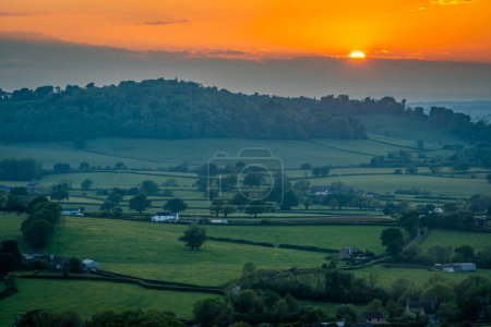 Schöner Sonnenuntergang in der englischen Landschaft in der Nähe von Batcombe im Dorset County, untergehende Sonne und dramatische Wolken über den Hügeln und Ackerland