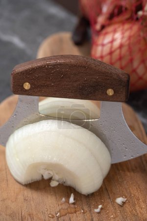 Slicing an onion on wooden cutting board with an Alaskan ulu knife.