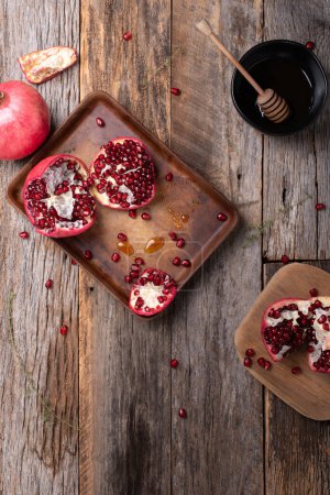Photo for Fresh, ripe pomegranate with thyme and drizzle of honey on a wooden background. - Royalty Free Image