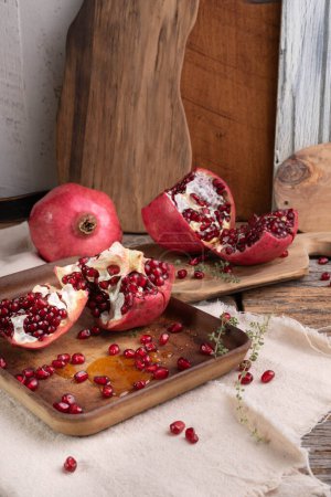 Photo for Fresh, ripe pomegranate with thyme and drizzle of honey on a wooden background.  Selective focus. - Royalty Free Image