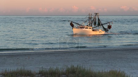 Téléchargez les photos : Bateau de crevettes le long du littoral de la Caroline du Nord à la lumière du soleil couchant. - en image libre de droit