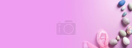 Photo for Easter holiday purplish pink banner background with fluffy bunny ears and eggs of various sizes and shapes. - Royalty Free Image