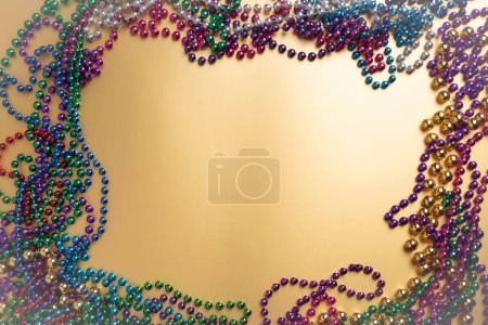 Mardi Gras beads on a golden background. Party invitation, greeting card, carnival celebration concept.
