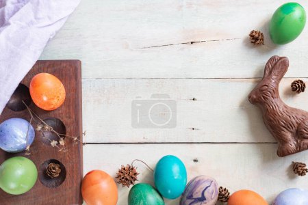 Easter background.  Colorful dyed eggs with a chocolate bunny on plank background.