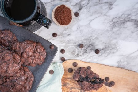 Photo for Gooey, double chocolate cookies, fresh out of oven.  Coffee, chocolate-chips and dark cocoa powder, marble countertop. - Royalty Free Image