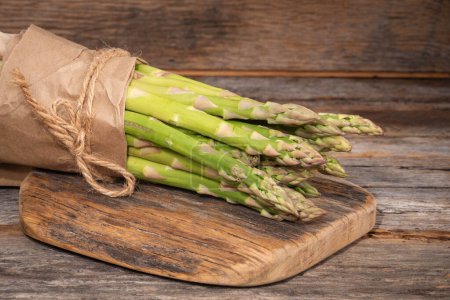 Photo for Bunch of branches of fresh green asparagus on wooden background, side view. - Royalty Free Image