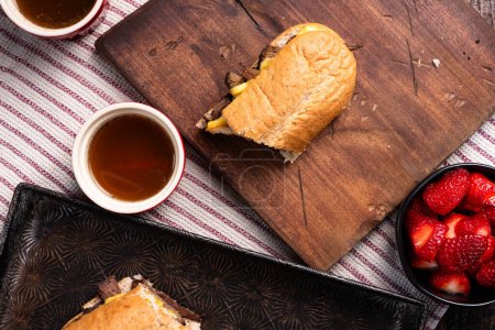 Foto de Sandwich francés con queso gouda ahumado. Lados de au jus y fresas frescas. - Imagen libre de derechos