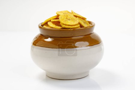 Foto de Chips de Kerala o chips de plátano, elemento de merienda de culto de Kerala, dispuestos tradicionalmente en maceta de cerámica, bharani, imagen aislada con fondo blanco - Imagen libre de derechos