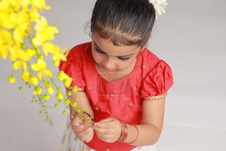 Una linda niña pequeña con Kerala vestido de color dorado falda larga y blusa roja con flor de ducha de oro, aislado 