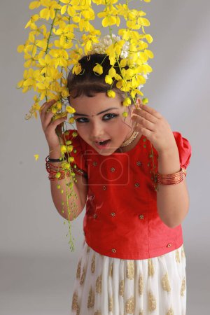 Ein nettes kleines Mädchen Kind trägt Kerala Kleid-goldene Farbe langen Rock und rote Bluse mit goldener Duschblume, isoliert 