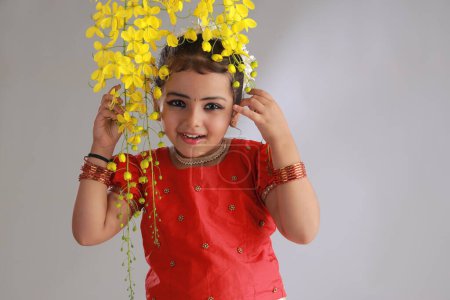 Photo for A cute small girl child wearing  Kerala dress-golden colour long skirt and red blouse with golden shower flower ,isolated - Royalty Free Image