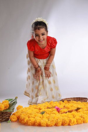 Photo for A cute small girl child wearing  Kerala dress-golden colour long skirt and red blouse,onam festival theme, isolated white background. - Royalty Free Image