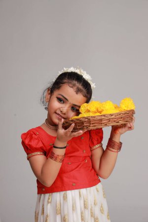 Une jolie petite fille enfant portant une jupe longue Kerala couleur or et chemisier rouge, thème du festival onam, fond blanc isolé.
