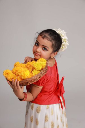 Una linda niña pequeña con vestido de Kerala de color dorado falda larga y blusa roja, tema del festival onam, fondo blanco aislado.