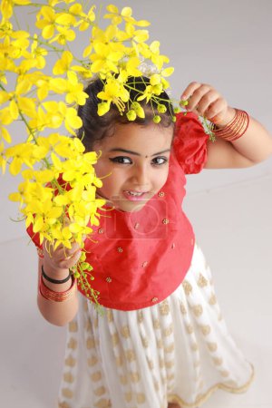 Photo for A cute small girl child wearing  Kerala dress-golden colour long skirt and red blouse with golden shower flower ,isolated - Royalty Free Image