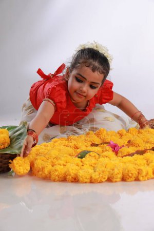 Foto de Una linda niña pequeña con vestido de Kerala de color dorado falda larga y blusa roja, tema del festival onam, fondo blanco aislado. - Imagen libre de derechos