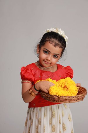 Foto de Una linda niña pequeña con vestido de Kerala de color dorado falda larga y blusa roja, tema del festival onam, fondo blanco aislado. - Imagen libre de derechos