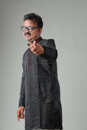 Téléchargez les photos : Un homme avec un costume traditionnel indien, avec un fond uni, isolé, portant kurta noir et pyjama blanc. - en image libre de droit