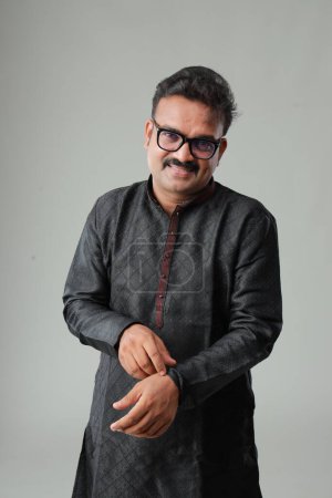 Téléchargez les photos : Un homme avec un costume traditionnel indien, avec un fond uni, isolé, portant kurta noir et pyjama blanc. - en image libre de droit