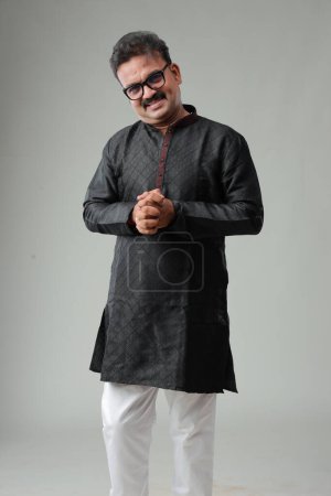 Foto de Un hombre con traje tradicional indio, con fondo liso, aislado, con kurta negra y pijama blanco. - Imagen libre de derechos