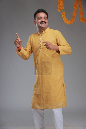 Téléchargez les photos : Un homme avec un costume traditionnel indien, avec un fond uni, isolé, portant kurta jaune et pyjama blanc. - en image libre de droit