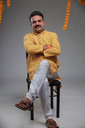 Téléchargez les photos : Un homme avec un costume traditionnel indien, avec un fond uni, isolé, portant kurta jaune et pyjama blanc. - en image libre de droit