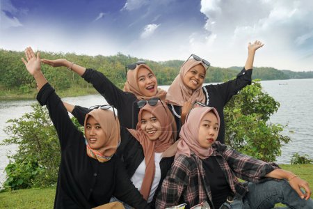 Photo for Five beautiful young asian muslim hijab women on vacation together with a lake and blue sky in the background - Royalty Free Image