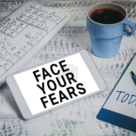 Photo for Text showing inspiration Face Your Fears, Business approach Strong and confident to look into the future to success Important Idea Shown On Phone On Desk With Cup With Pencils And Books. - Royalty Free Image