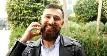 Téléchargez les photos : Jeune homme barbu se brossant la barbe en plein air. - en image libre de droit