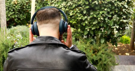 Foto de Hombre guapo en auriculares escuchando música al aire libre
. - Imagen libre de derechos