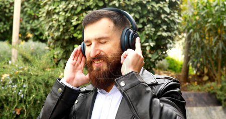 Foto de Hombre guapo en auriculares escuchando música al aire libre
. - Imagen libre de derechos