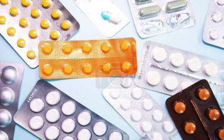 Téléchargez les photos : Close-up view of scattered blister packs with different pills on blue background - en image libre de droit