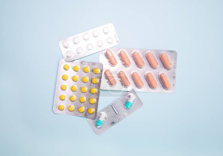 Photo for Close-up view of scattered blister packs with different pills on blue background - Royalty Free Image