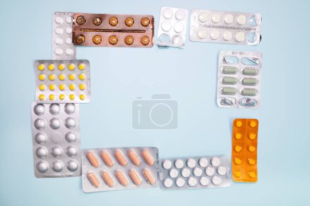 Foto de Close-up view of scattered blister packs with different pills on blue background - Imagen libre de derechos
