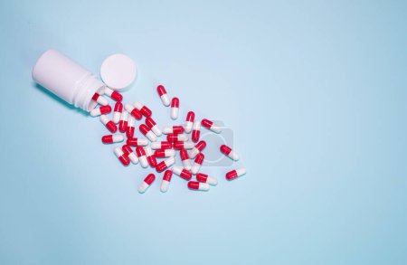 Téléchargez les photos : Medicine bottle and pills spilled on a light blue background. Medicines and prescription pills background - en image libre de droit